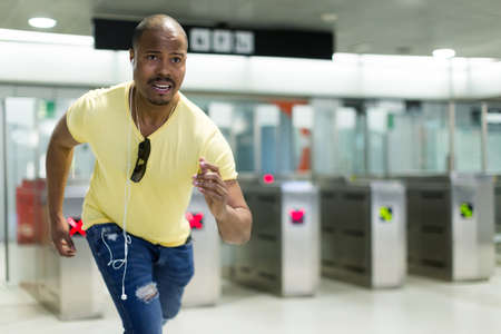 Young man passenger running to train at modern metro stationの写真素材