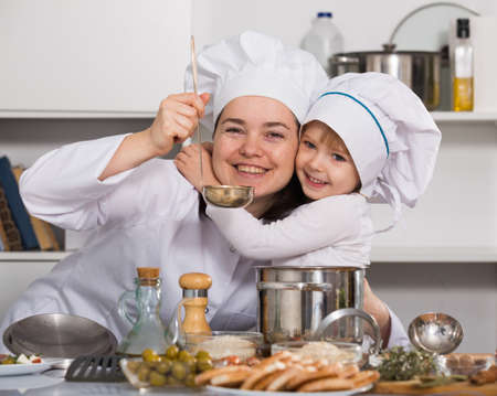 Woman with her daughter are tasting the soup in time cookingの写真素材