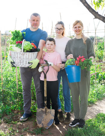 Family posing in garden with picked vegetablesの写真素材