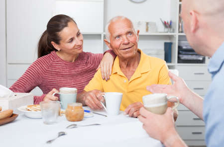 Smiling father, daughter and son-in-law drinking tea at homeの写真素材