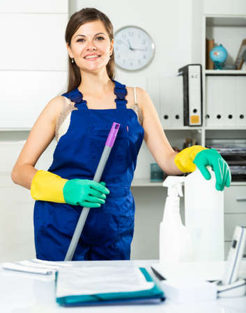 Young female cleaner in protective uniform at company officeの写真素材