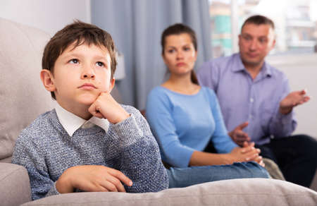 Upset boy scolded by mother and fatherの写真素材