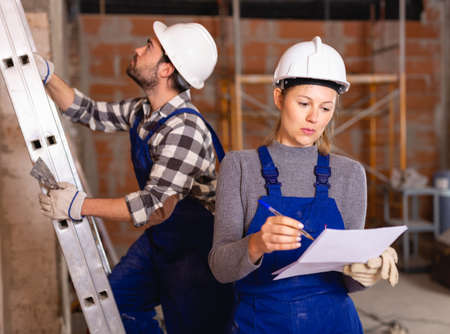 Female foreman checking the work of the builders in houseの写真素材