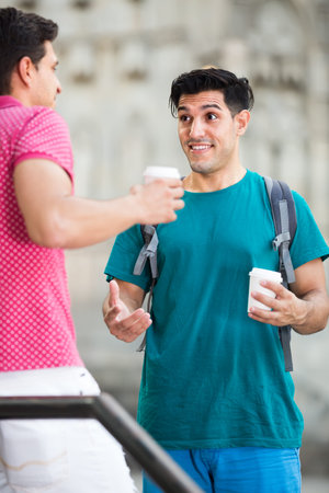 cheerful male fans are drinking coffee and talking in Barcelona