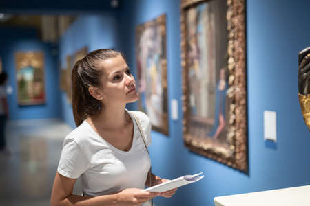 Young woman looking at artworks in museumの写真素材