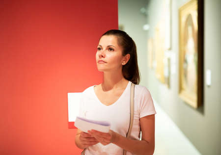Young woman looking at artworks in museumの写真素材
