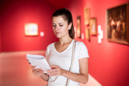 Young woman looking at artworks in museumの写真素材