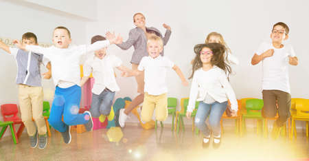 Children with teacher jumping together in schoolroomの写真素材