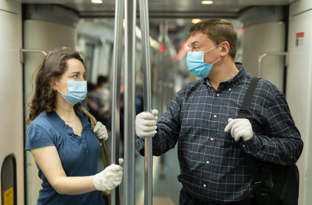 Man and woman in medical masks talking in subway