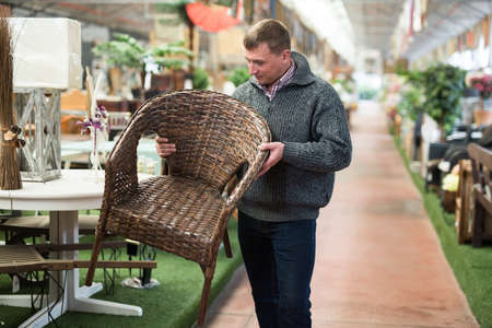 Man looking for wicker armchair in furniture salonの写真素材