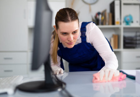 Smiling woman in uniform making cleaning in the office
