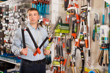 Man choosing new secateurs in garden equipment shop