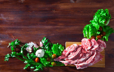 Wooden background with raw lamb, vegetables, greensの写真素材