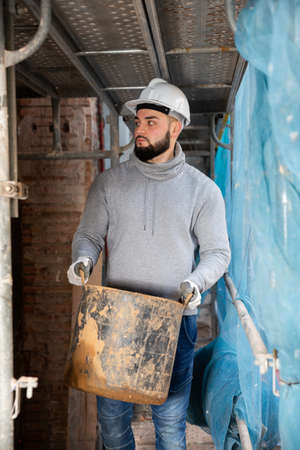 Contractor carrying bucket with cement mortarの写真素材