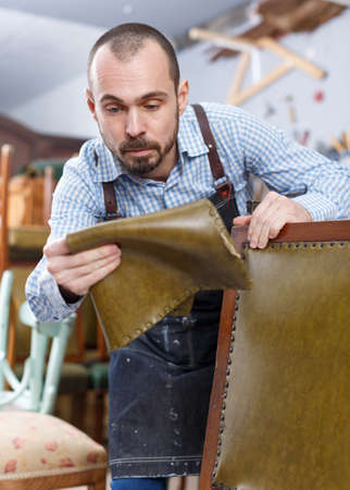 Craftsman reupholstering chair in workshopの写真素材