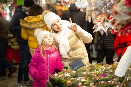 Smiling woman with small daughter in Christmas marketの写真素材
