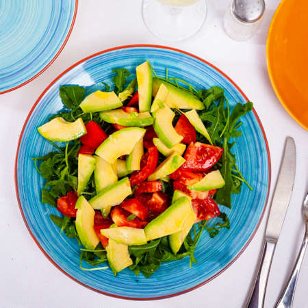Tasty salad with avocado, tomatoe and arugula at plateの写真素材