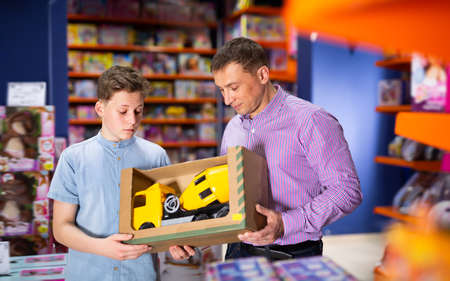 Fine teenage boy with father buying toy carの写真素材