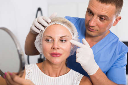 Doctor is examining woman patient behind mirror before the procedureの写真素材