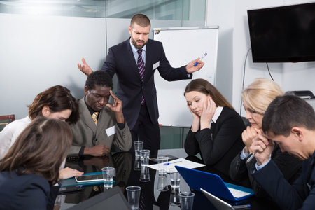 Angry businessman berating managers pointing out shortcomings