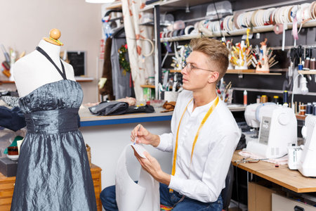 Fashion designer standing near tailor mannequin