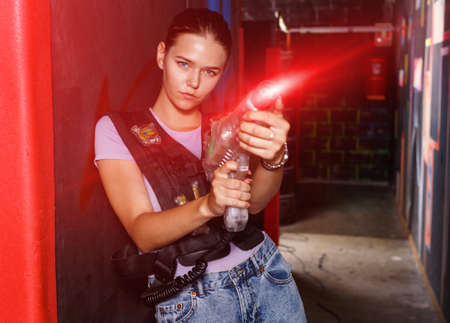 Portrait of young girl took aim colored laser guns during laserの写真素材