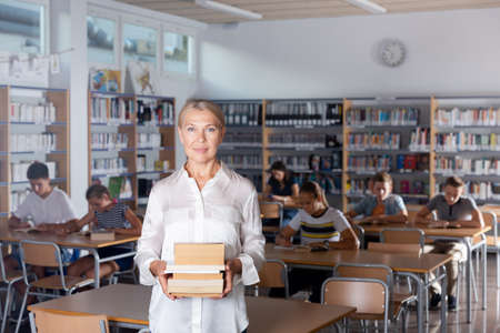 Portrait of mature woman teacher standing with booksの写真素材
