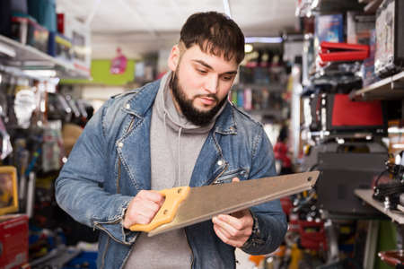 Man chooses hand saw in hardware storeの写真素材