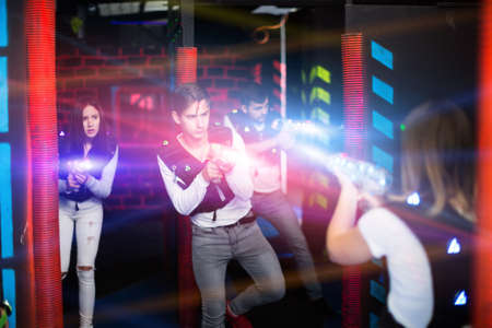 Emotional guy playing laser tag in colorful beamsの写真素材