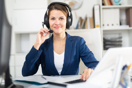 Smiling young female operator talking with customer using headset at office