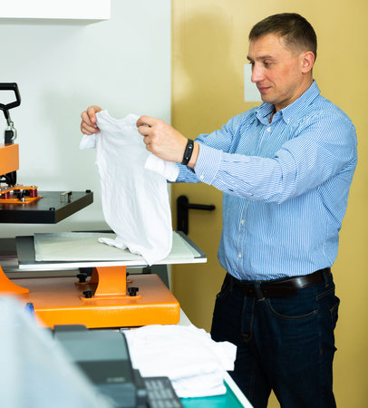 Man using a serigraph press to print a shirt in a workshop