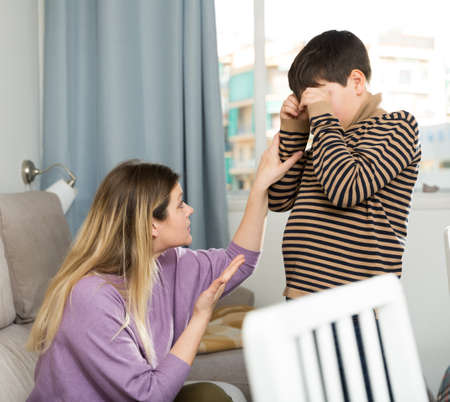 Son crying and unhappy mom during quarrel in homeの写真素材