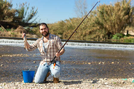 Happy fisherman on the river bank on a sunny dayの写真素材
