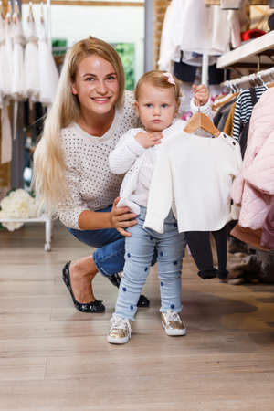 Woman and daughter buying kids clothesの写真素材