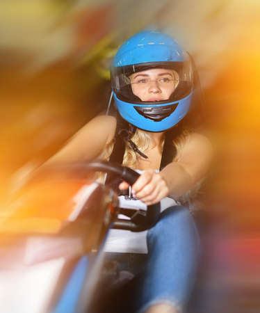 Girl and her friends competing on racing cars at kart circuitの写真素材