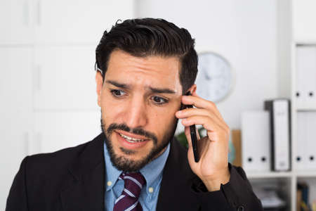 Adult man is surprised while talking phone with his partnerの写真素材