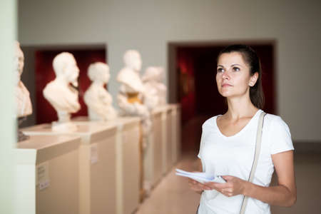 Woman observing sculptures exposition in art museumの写真素材