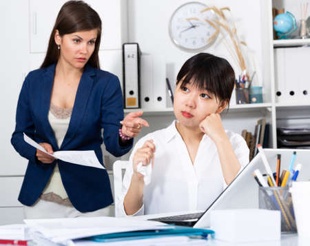Upset asian woman with angry bossの写真素材