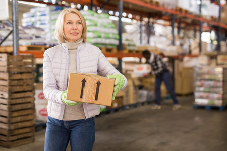 Female warehouse worker carrying cardboard boxes