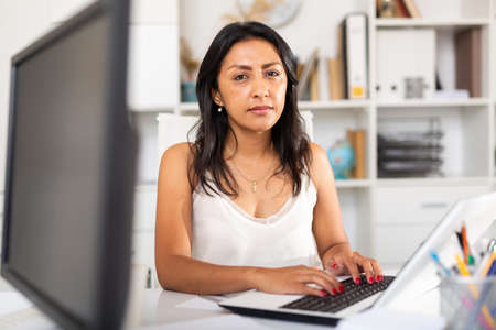 Confident female office employee working with laptopの写真素材