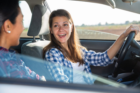Portrait of happy female driver and friend in car