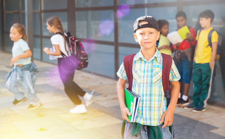 Smiling primary school boy standing outdoors