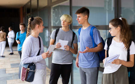 Teen students friendly talking near college buildingの写真素材