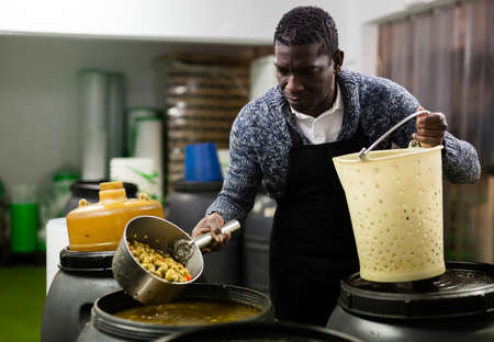 Afro-american man takes olives from barrel with colanderの写真素材