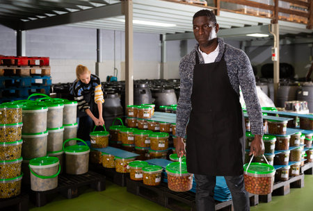 Man arranging plastic buckets with pickled olives
