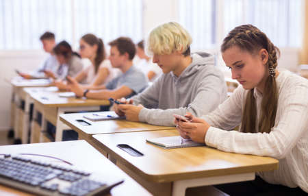 Teenage students using smartphones during lessonの写真素材
