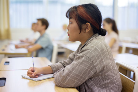 Japanese teenage schoolgirl writing lectures during lesson