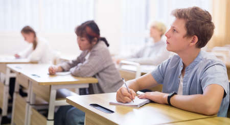 Teen boy sitting at desk in classroomの写真素材