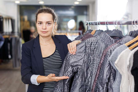 Shop assistant demonstrating coat in shopの写真素材