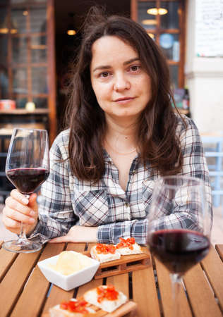 Woman on open terrace of restaurant with wine and snacksの写真素材